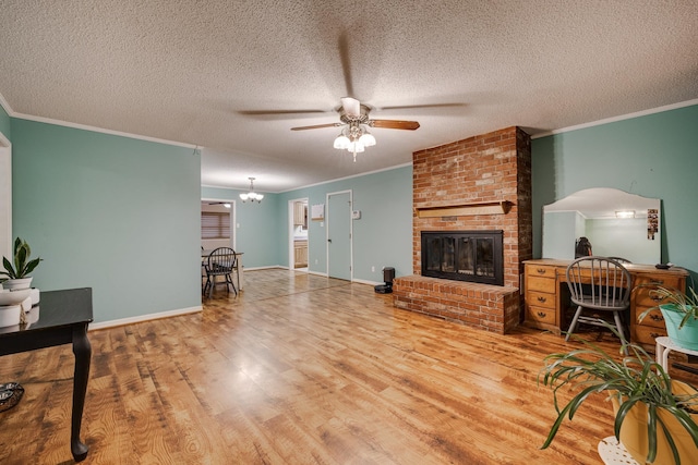 living room with a fireplace, ceiling fan with notable chandelier, wood-type flooring, and ornamental molding