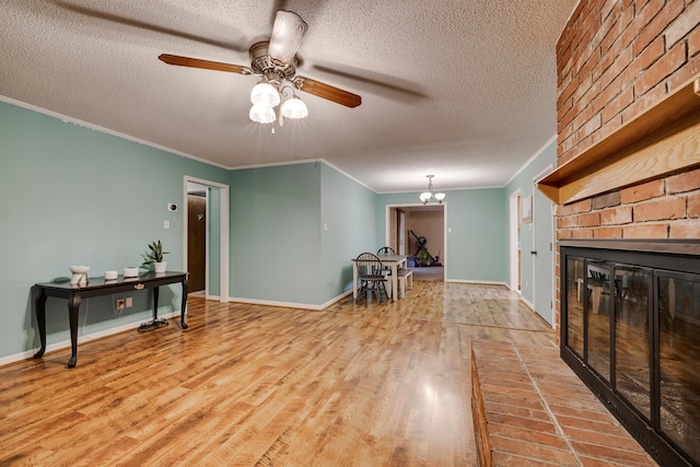 interior space featuring ceiling fan with notable chandelier, hardwood / wood-style floors, a fireplace, ornamental molding, and a textured ceiling