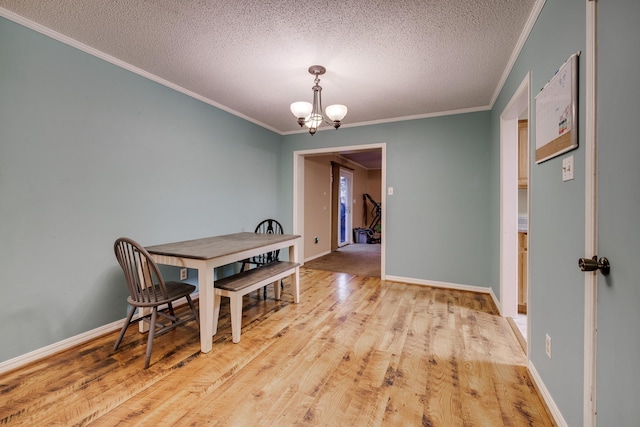 dining area featuring crown molding, light wood-type flooring, a textured ceiling, and an inviting chandelier