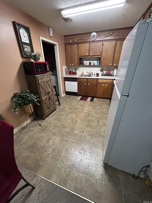 kitchen featuring sink, white appliances, and a textured ceiling