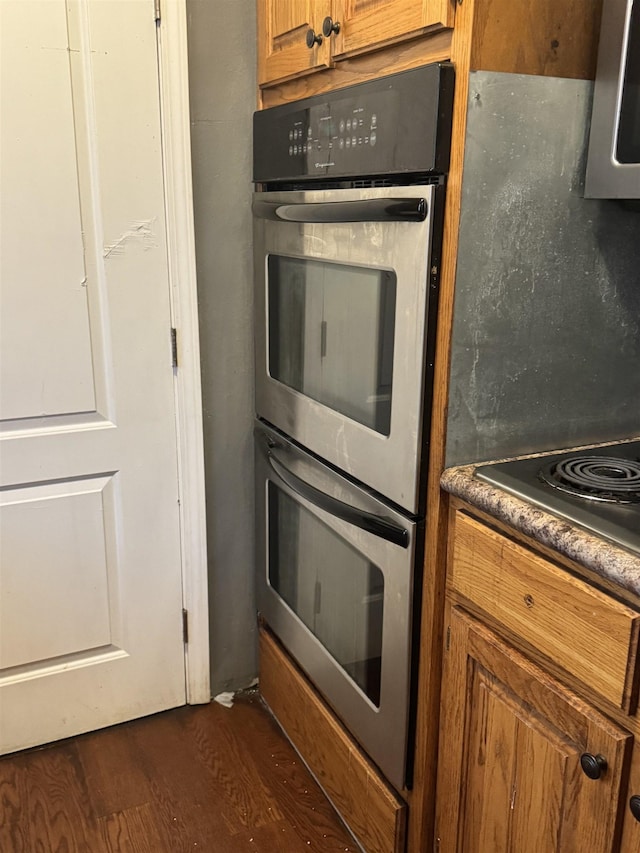 kitchen with dark hardwood / wood-style floors, cooktop, and stainless steel double oven