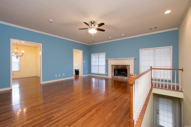 unfurnished living room featuring ornamental molding, wood-type flooring, a fireplace, and ceiling fan with notable chandelier