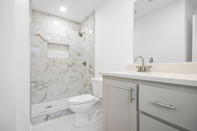 bathroom featuring vanity, toilet, and tiled shower