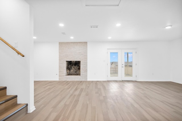 unfurnished living room featuring light hardwood / wood-style flooring, a fireplace, and french doors