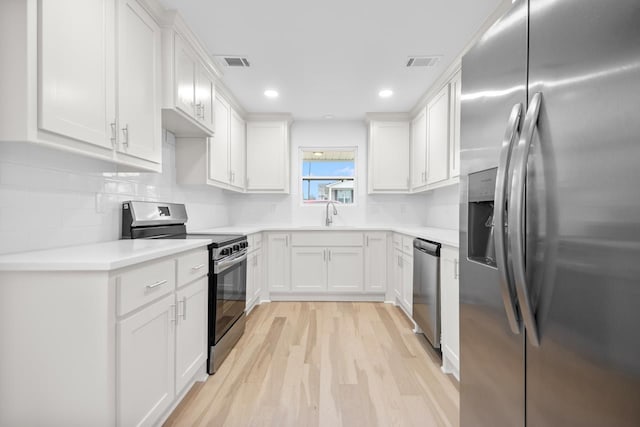 kitchen with stainless steel appliances, white cabinets, light wood-type flooring, and decorative backsplash