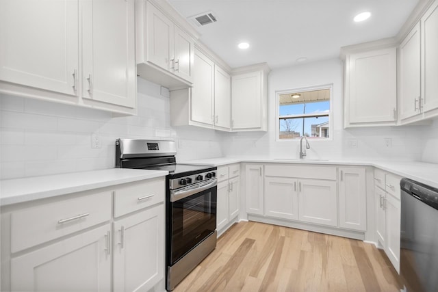 kitchen with sink, white cabinetry, tasteful backsplash, light hardwood / wood-style flooring, and stainless steel appliances