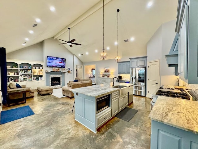 kitchen featuring pendant lighting, sink, a kitchen island with sink, stainless steel appliances, and light stone counters