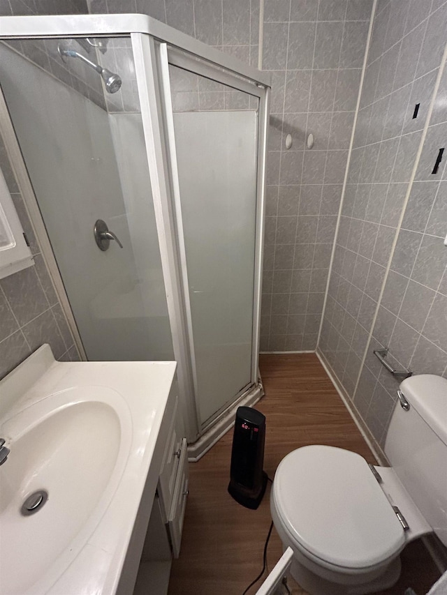 bathroom featuring toilet, an enclosed shower, wood-type flooring, tile walls, and vanity