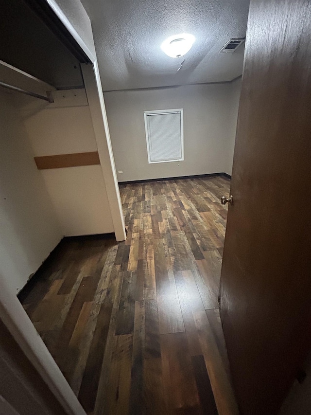 hall featuring dark wood-type flooring and a textured ceiling