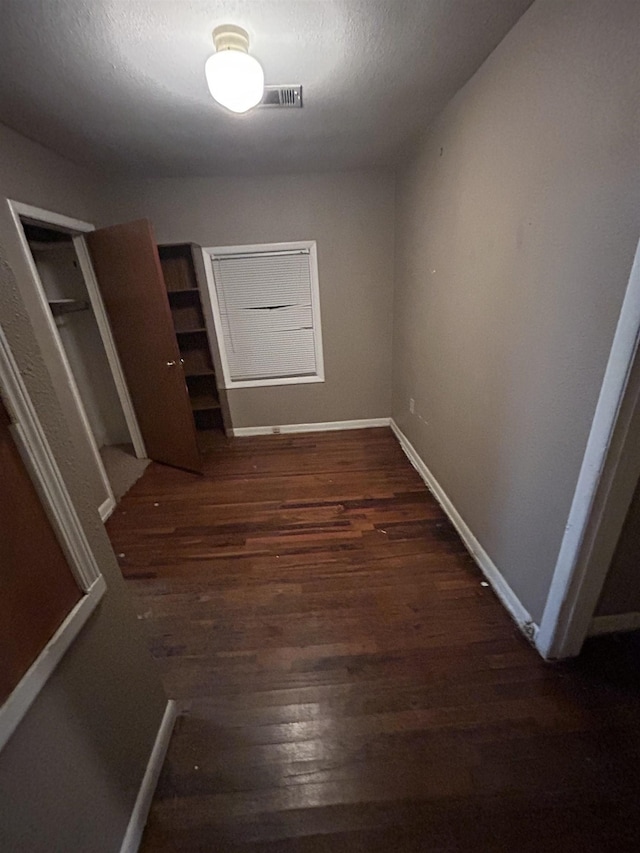 hall featuring a textured ceiling and dark hardwood / wood-style flooring