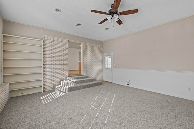 unfurnished living room with a textured ceiling, carpet floors, and ceiling fan