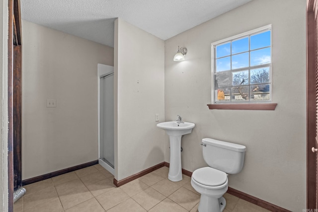 bathroom with toilet, tile patterned floors, a textured ceiling, and a shower with shower door