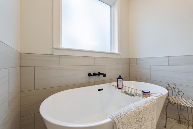 bathroom featuring a tub to relax in, sink, and tile walls