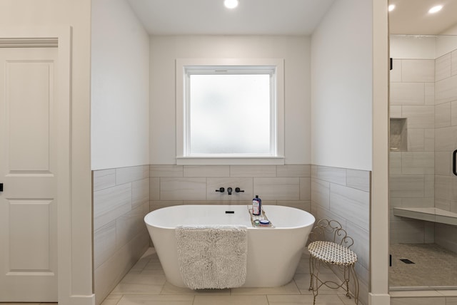 bathroom with tile walls and separate shower and tub