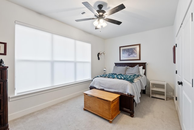 carpeted bedroom with ceiling fan, multiple windows, and a closet