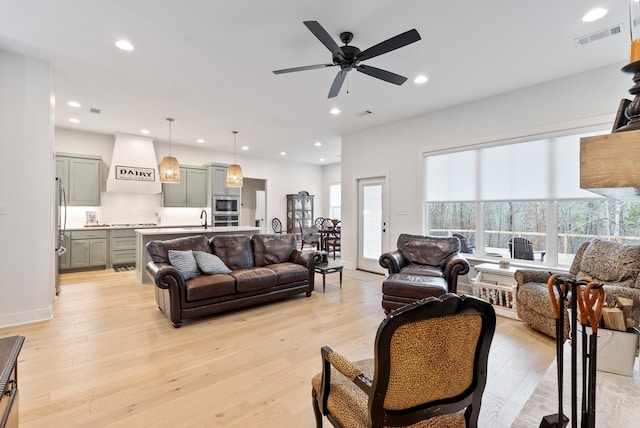 living room with ceiling fan, sink, and light hardwood / wood-style floors