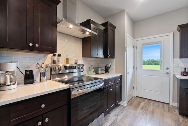 kitchen featuring light wood-type flooring, electric range, dark brown cabinetry, and wall chimney exhaust hood