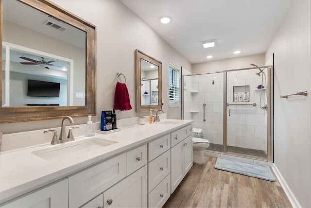 bathroom with hardwood / wood-style flooring, vanity, a shower with door, and toilet