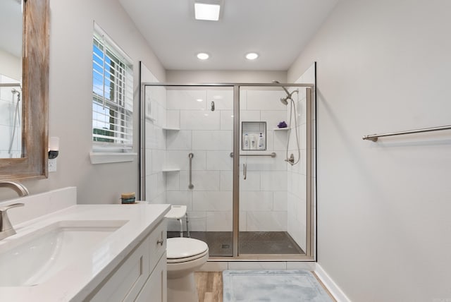 bathroom featuring vanity, a shower with shower door, and toilet