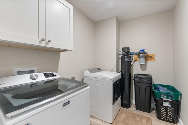 laundry area featuring separate washer and dryer, light hardwood / wood-style floors, and cabinets