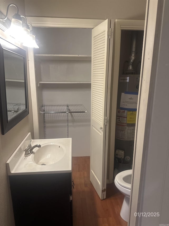 1013 Elm St, Coal Hill, AR 72832 - bathroom with gas water heater, wood-type flooring, vanity, and toilet