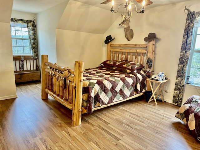 bedroom featuring vaulted ceiling, ceiling fan with notable chandelier, and hardwood / wood-style floors