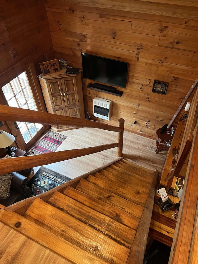 stairs featuring hardwood / wood-style flooring, heating unit, and wood walls