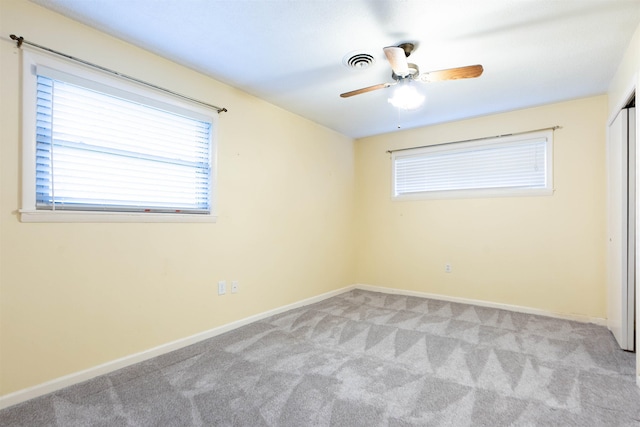empty room with light carpet, visible vents, baseboards, and a ceiling fan