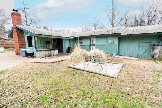 back of property with a chimney, metal roof, a patio, and fence
