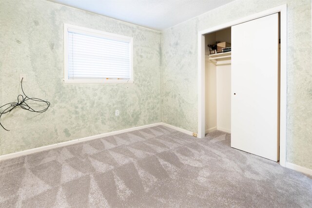 unfurnished bedroom with carpet flooring, baseboards, and a closet