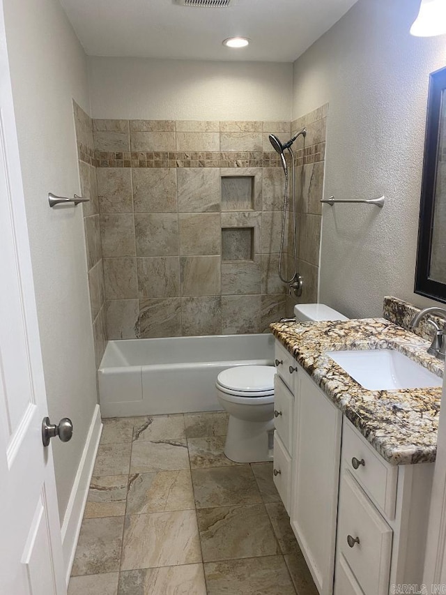 full bathroom featuring vanity, tiled shower / bath combo, and toilet