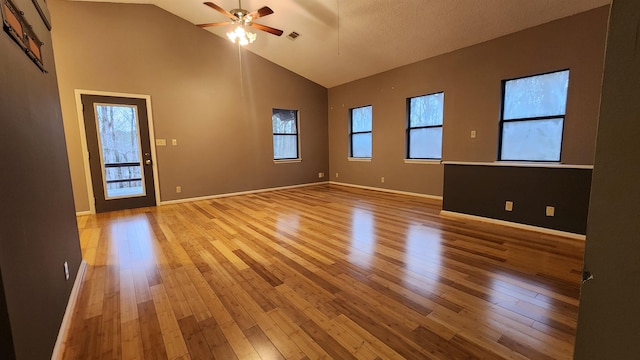 empty room with ceiling fan, high vaulted ceiling, and light hardwood / wood-style flooring