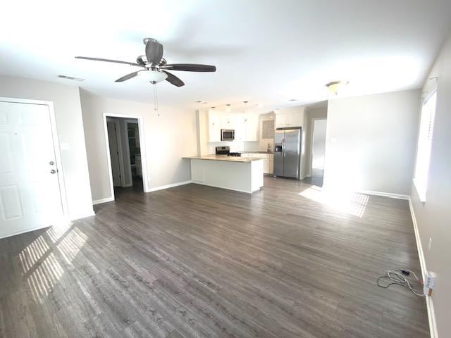 unfurnished living room featuring dark wood-type flooring and ceiling fan