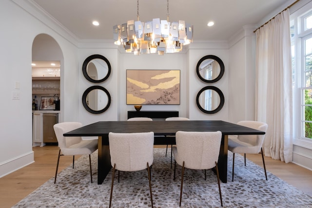 dining space with ornamental molding, a healthy amount of sunlight, and light wood-type flooring