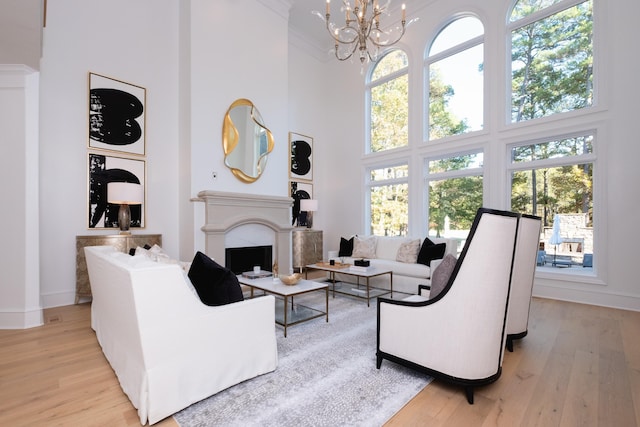 living room with an inviting chandelier, light hardwood / wood-style flooring, and a high ceiling