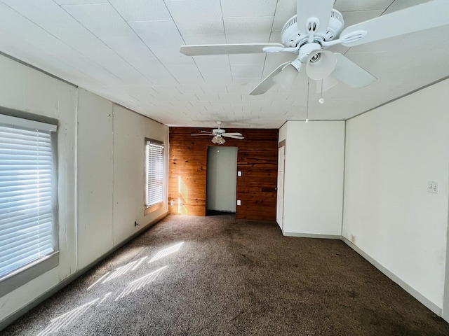 interior space with ceiling fan and wooden walls