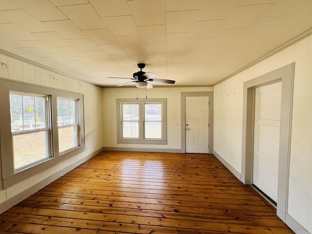 unfurnished room with hardwood / wood-style flooring, ceiling fan, ornamental molding, and wood walls