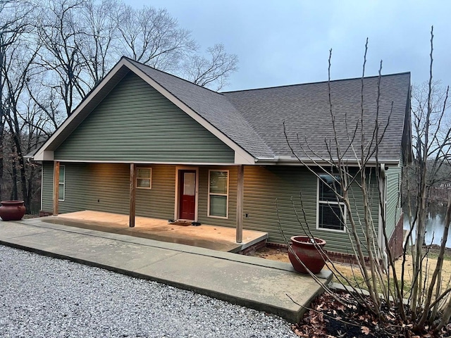 back of property with a shingled roof and a porch