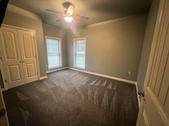 unfurnished bedroom with dark colored carpet, ceiling fan, and a closet