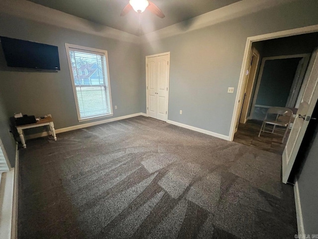 unfurnished bedroom featuring ceiling fan and dark carpet