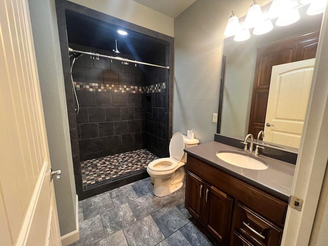 bathroom featuring tiled shower, vanity, and toilet