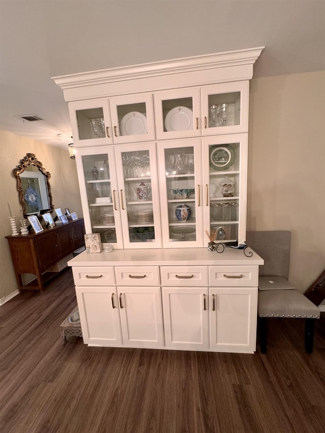 bar featuring dark wood-type flooring and white cabinets