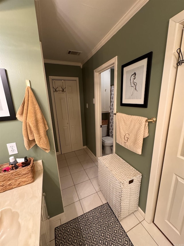 bathroom with tile patterned flooring, ornamental molding, and toilet