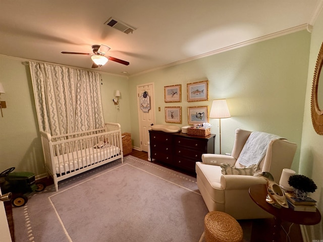 bedroom featuring ceiling fan, ornamental molding, carpet floors, and a crib