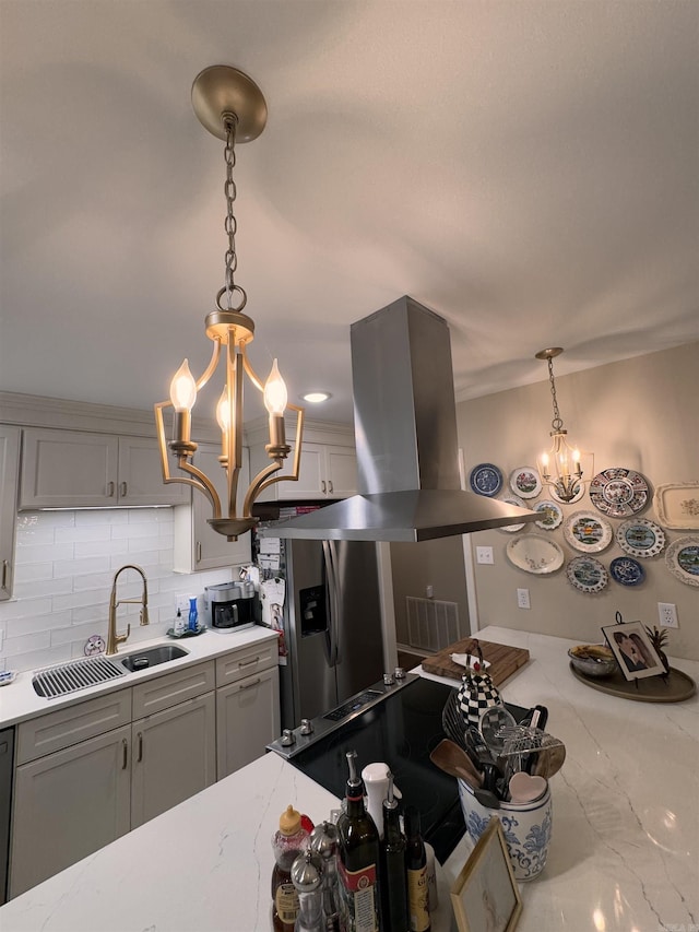 kitchen featuring hanging light fixtures, stainless steel refrigerator with ice dispenser, island exhaust hood, and a notable chandelier