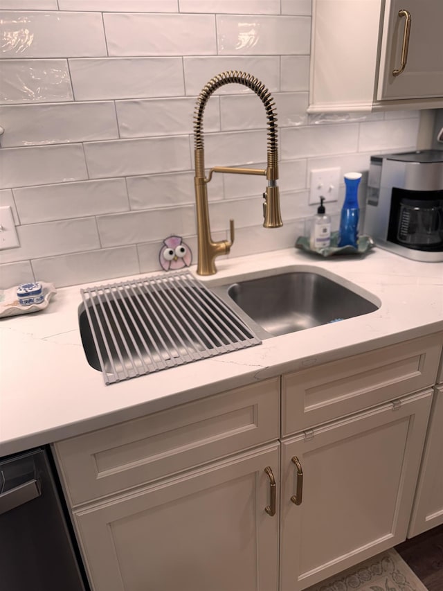 interior details with tasteful backsplash, black dishwasher, and light stone counters