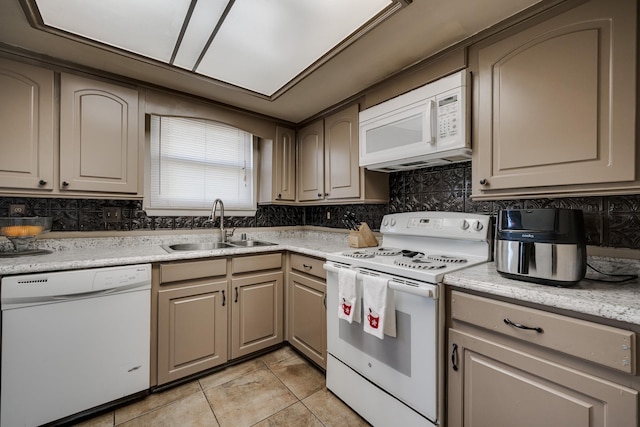 kitchen featuring tasteful backsplash, sink, light stone counters, and white appliances