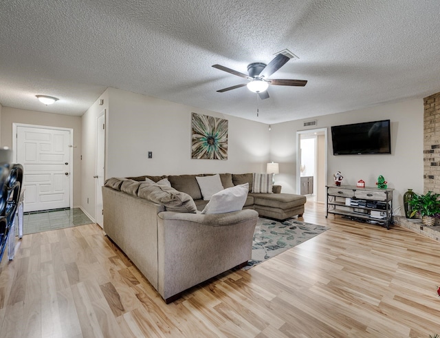 living room with ceiling fan, wood-type flooring, and a textured ceiling