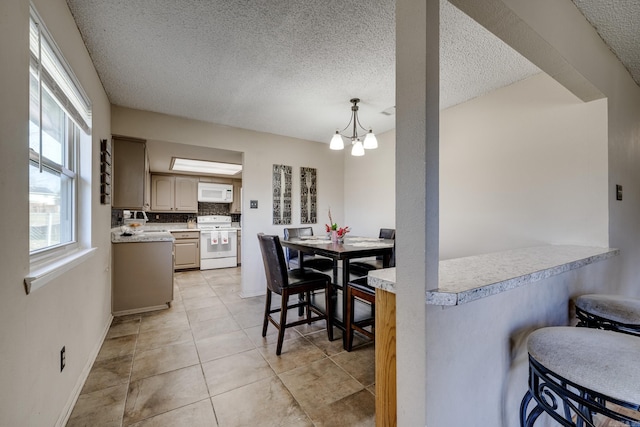 dining space featuring an inviting chandelier, sink, a textured ceiling, and light tile patterned floors