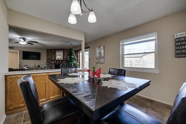 dining space with a notable chandelier, a textured ceiling, and dark tile patterned flooring